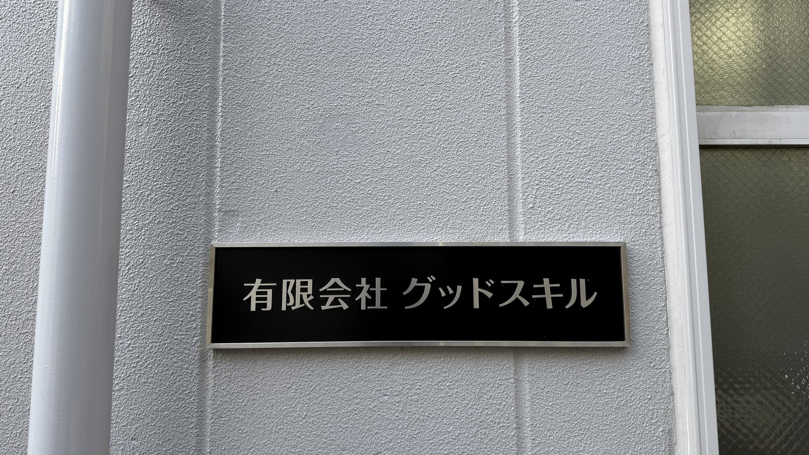 建物外壁に掲げられた有限会社グッドスキルの社名プレート