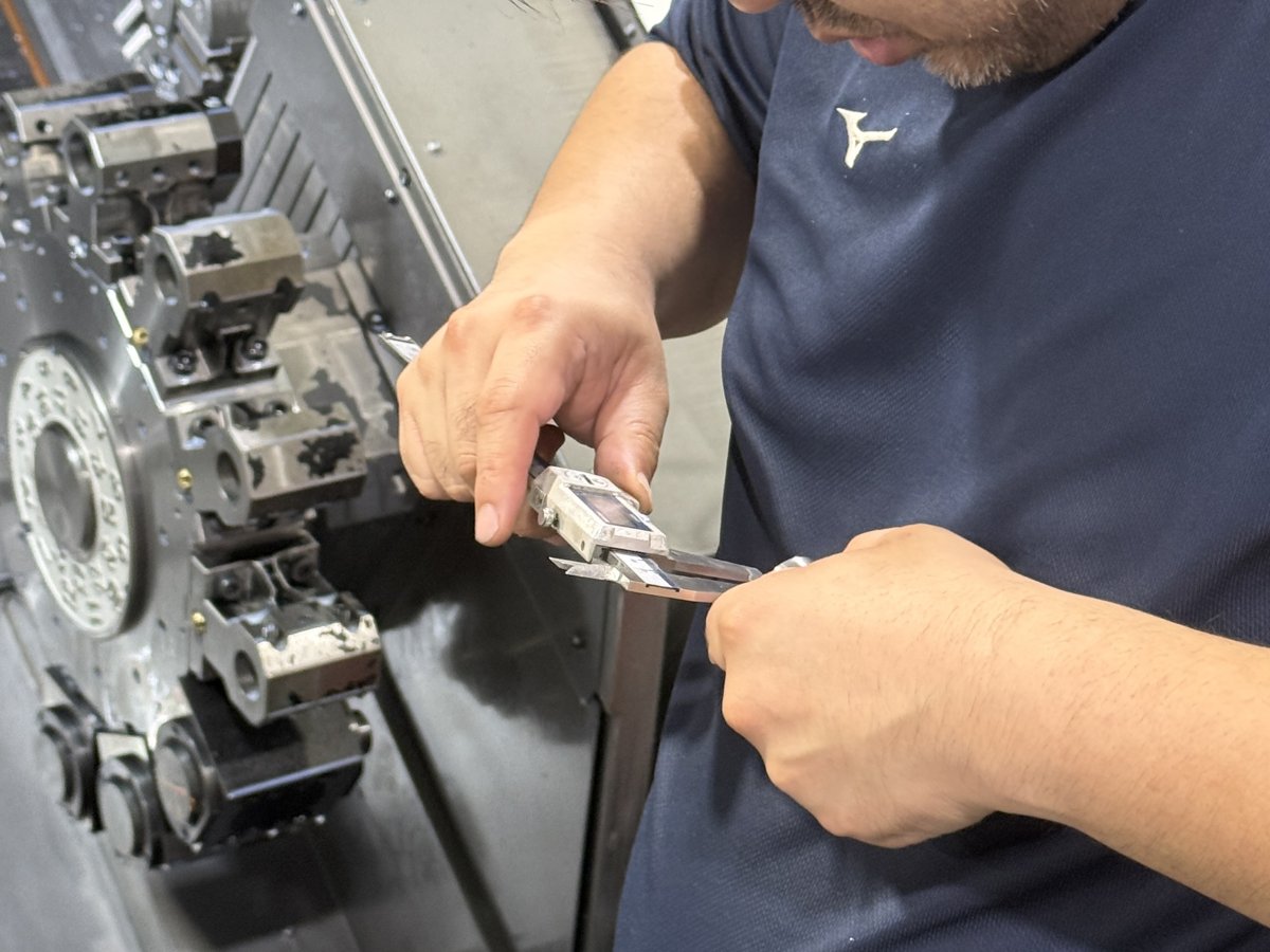機械の前で加工品を手に確認するスタッフ