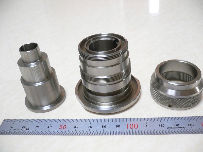 SUS304の加工品3点。段付きのブッシュ・ねじ付きハウジング・ローレット加工のリングで、スケール定規を添えて撮影